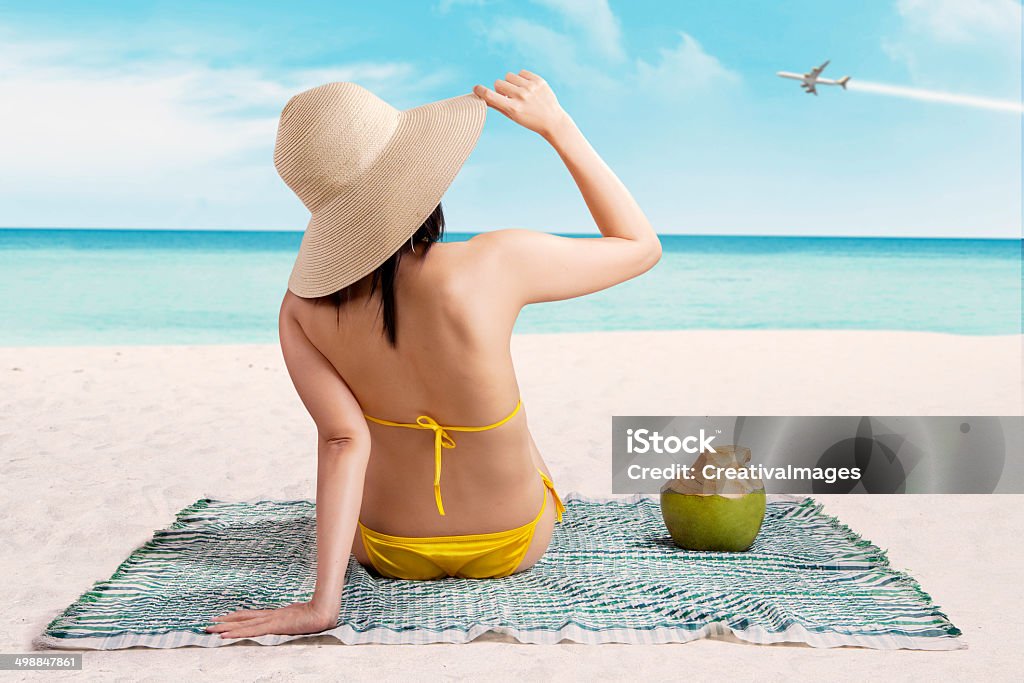 Woman in bikini enjoying summertime Woman in bikini sitting on the beach enjoying summertime Adult Stock Photo