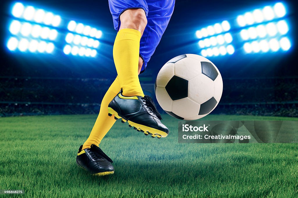 Soccer player kicking the ball Soccer player kicking the ball on the field at night Soccer Stock Photo