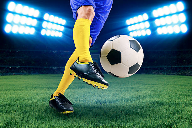 Soccer player kicking the ball Soccer player kicking the ball on the field at night soccer striker stock pictures, royalty-free photos & images