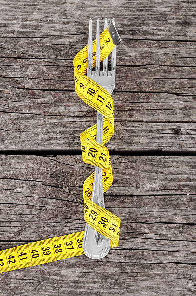 istock Fork and measuring tape on a thin wooden background 498849093