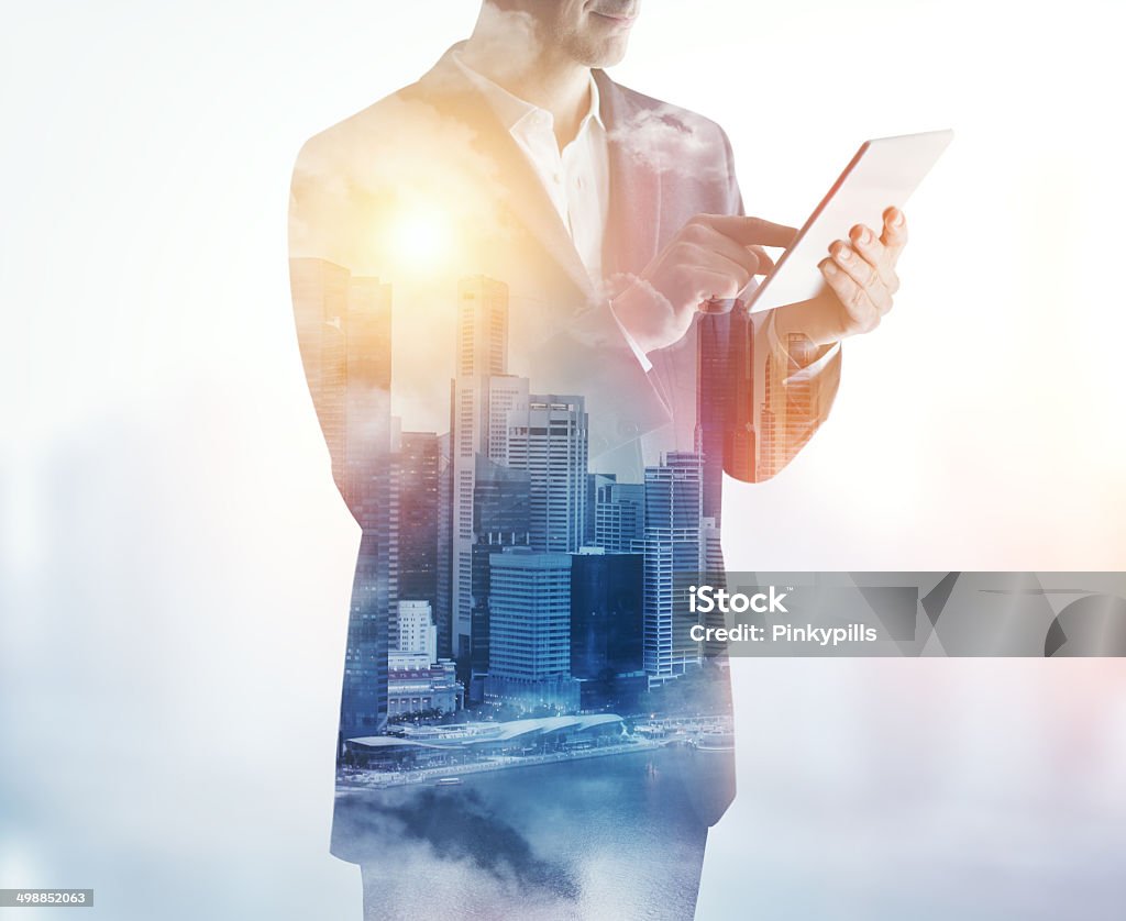 Double exposure of city and business man using digital tablet Adult Stock Photo