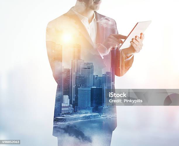Double Exposure Of City And Business Man Using Digital Tablet Stock Photo - Download Image Now