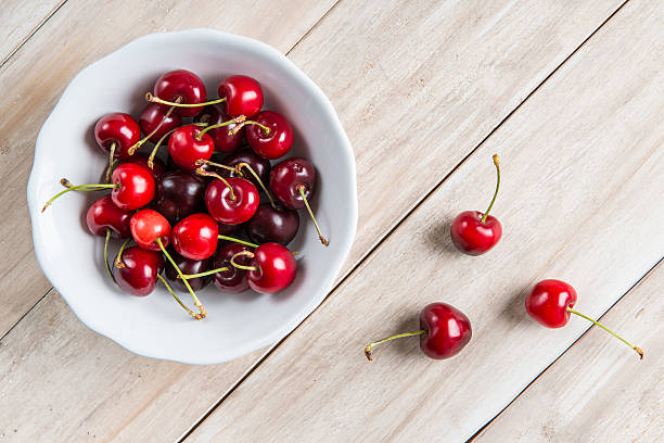 White bowl of cherries on the table stock photo