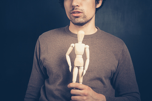 Young man is holding a wooden artist dummy