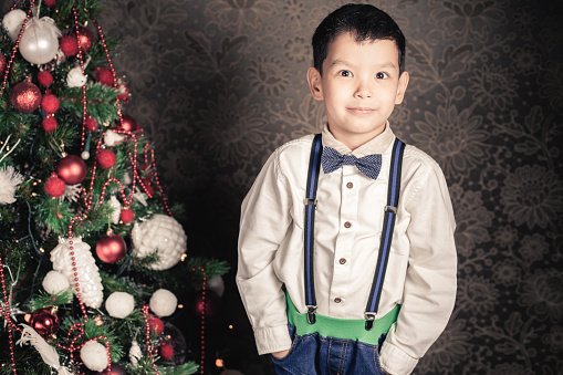 Handsome asian boy well dressed at Christmas holiday. Xmas and New Year holiday! Merry Christmas! Looking at the camera