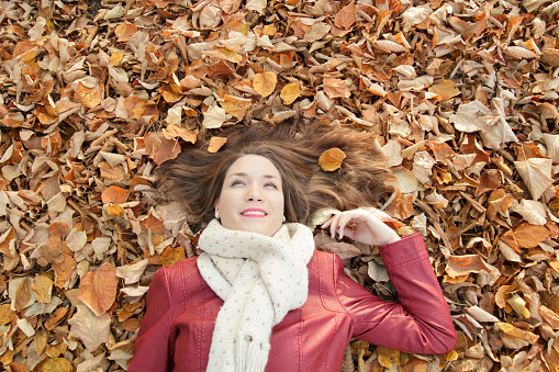 Young woman portrait, lying on leaves, top view