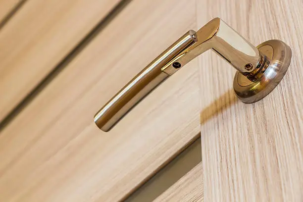 Modern gold-plated inner door handle in the room of a private house