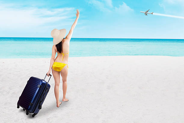 istock Woman in bikini with suitcase at beach 498879821