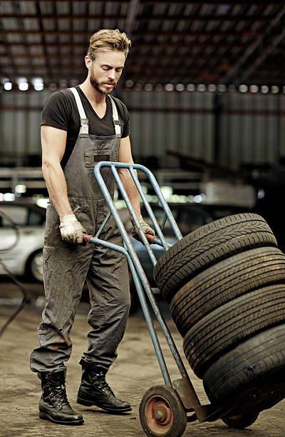 istock sexy mechanic transporting tires on carriage 498882976