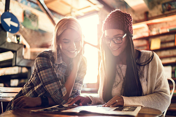 Smiling women relaxing while reading a magazine together.