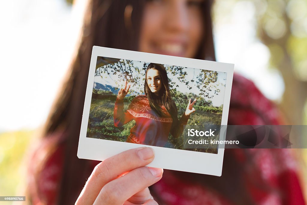 Young woman holding an instant photo Young woman holding an instant photo print where she is happy Holding Stock Photo