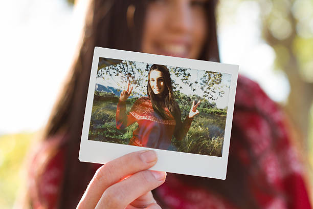 jovem mulher segurando uma foto instantânea - instant camera instant print transfer frame photograph imagens e fotografias de stock