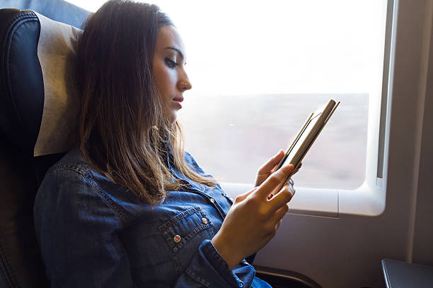 istock Beautiful young woman reading a book in the train. 498890958