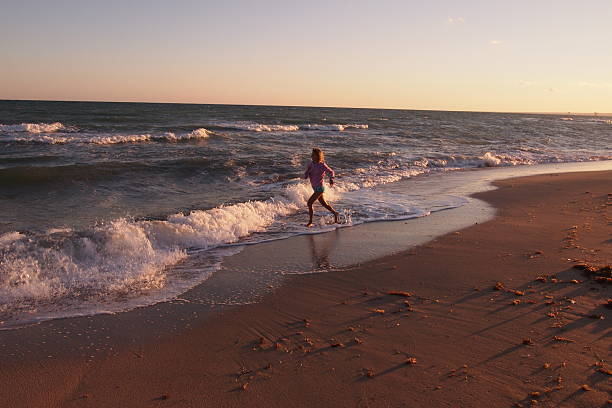Beautiful young girl running on beach stock photo