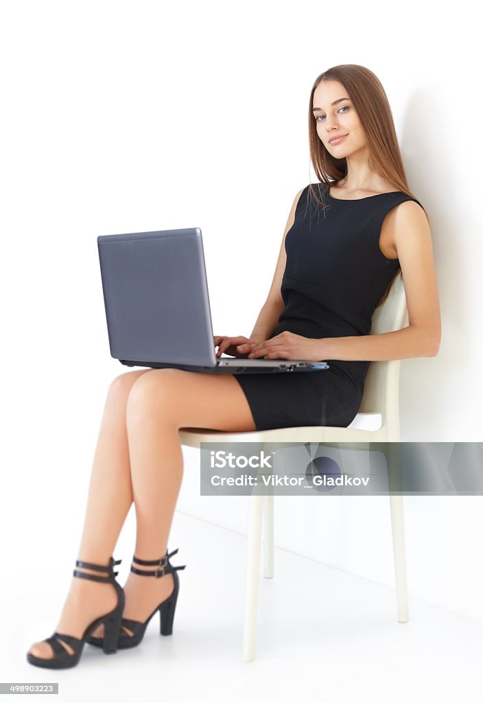 Young business woman with laptop Beautiful young business woman sitting on chair working with laptop on white background Businesswoman Stock Photo