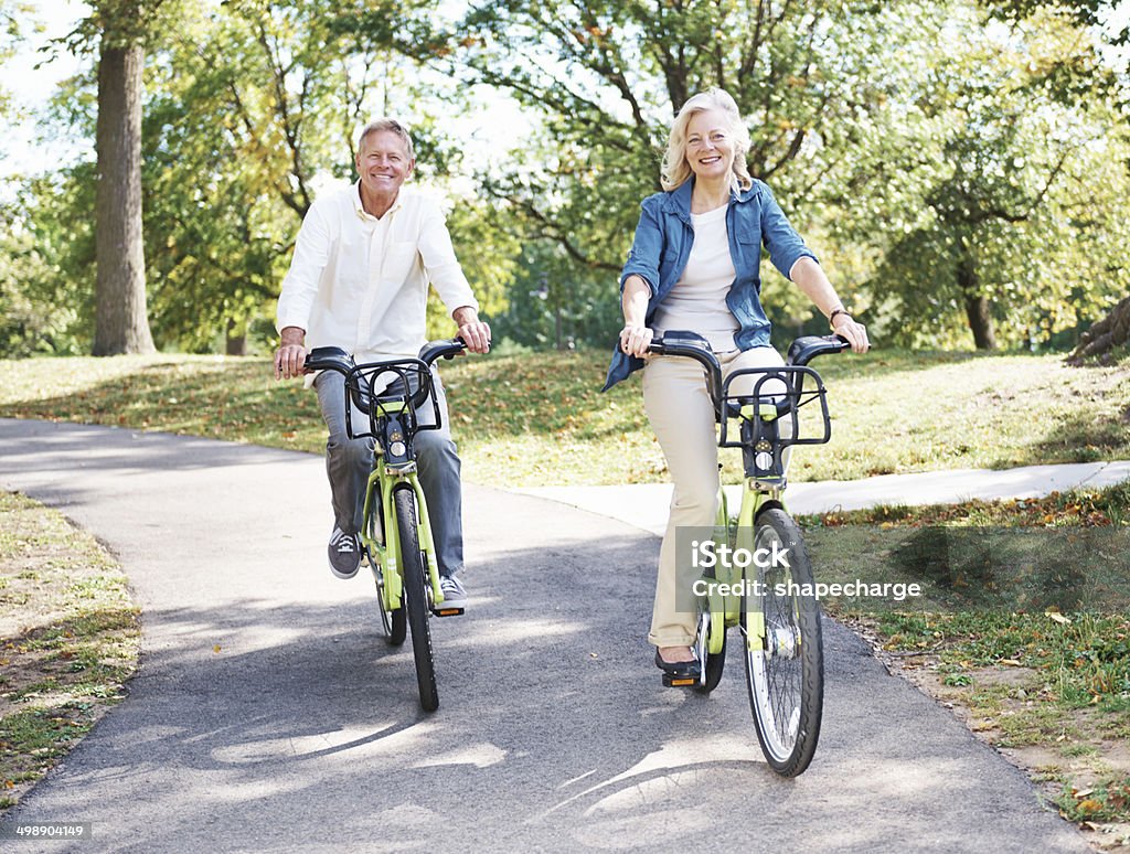 Rolling with my homie! Portrait of a happy senior couple enjoying a bicycle ride in the park together 60-69 Years Stock Photo