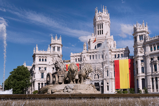 Fountain of Cibeles and the background the town hall decorated with Spanish flags. In the past it was the post office and communications