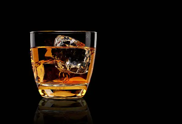 Whiskey in glass on black background