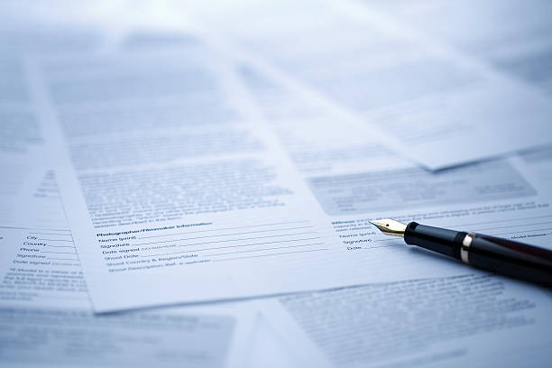 Contract A blue tinted image of Fountain pen lying on scattered legal contract documents on table, shot with very shallow depth of field legal document stock pictures, royalty-free photos & images