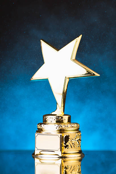 istock gold star trophy against blue particles background 498910298