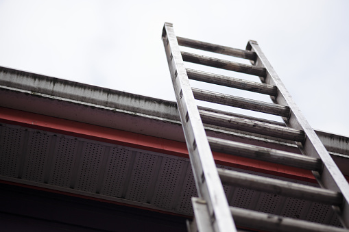 three section aluminum ladder leaning against house