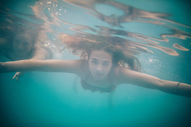 istock Girl looking at the camera while swimming underwater in pool 498917984