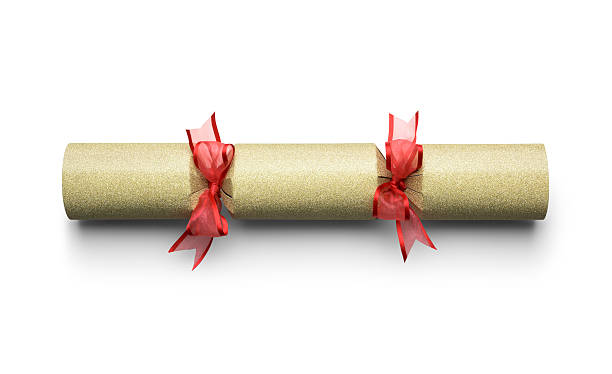 Christmas cracker isolated on white with a clipping path One sparkling gold Christmas cracker isolated on a white background with a clipping path. The cracker is covered in gold glitter and tied with a semi transparent red ribbon bow. This is a traditional table decoration for Christmas day and the holiday season. It has a soft drop shadow beside it. christmas cracker stock pictures, royalty-free photos & images