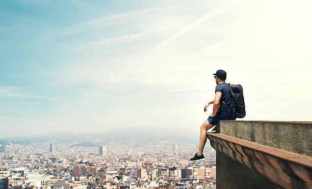Young man is sitting on a roof and looking city Young man is sitting on a roof and looking city free running stock pictures, royalty-free photos & images