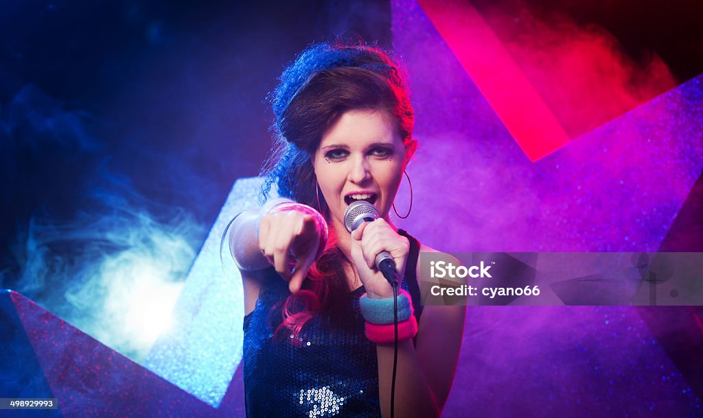 Young rock star performing Young beautiful girl singing on stage with star on background. Talent Show Stock Photo