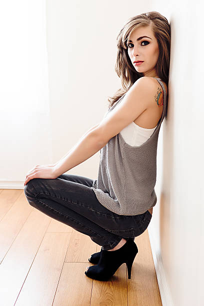 istock Beautiful young woman sitting against wall 498941548