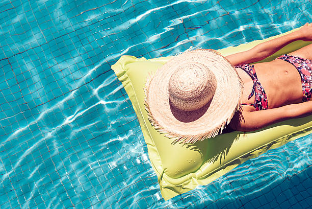 menina com chapéu de palha no airbed movimentando-se na piscina - teenage girls ideas blue yellow - fotografias e filmes do acervo