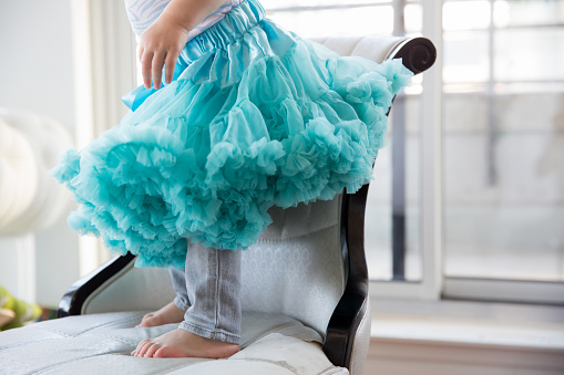 Cute little girl wearing a blue tutu standing on a chair