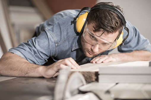 Focused carpenter at work with wooden plank