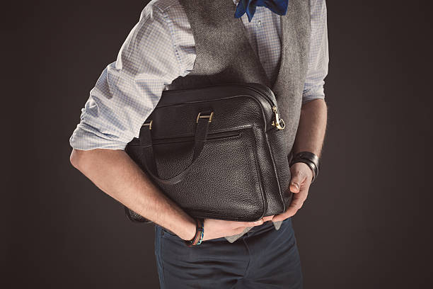 istock Elegant man holding bag, black background 498942552