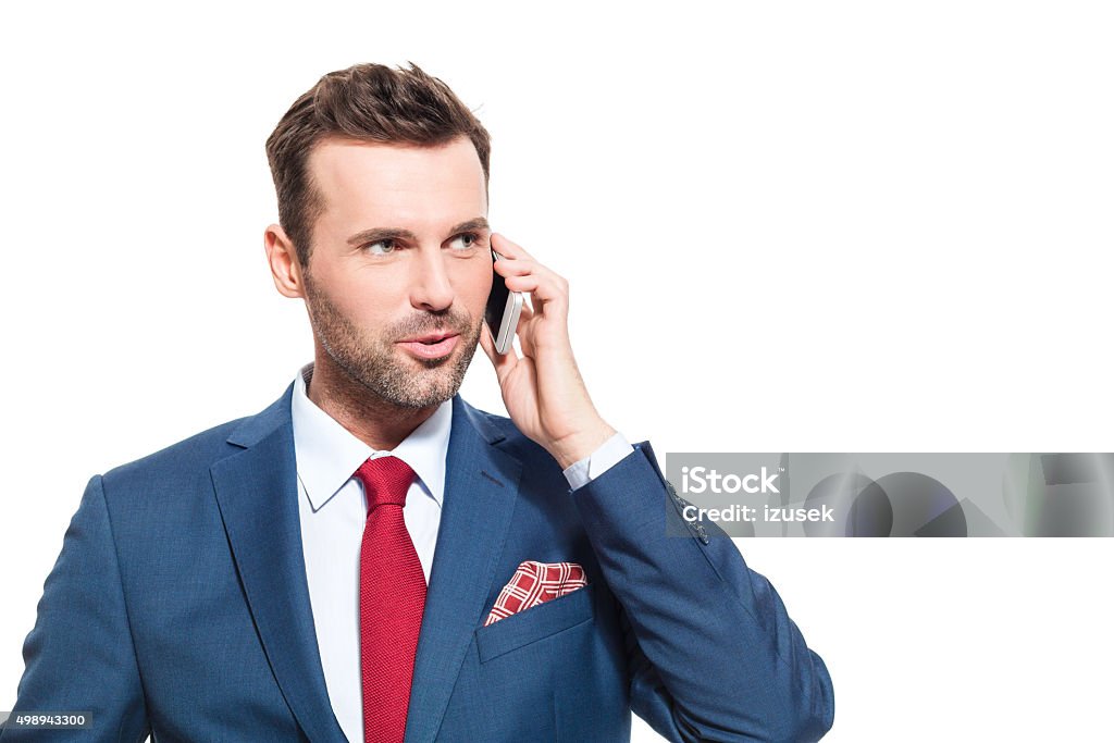 Confident businessman wearing suit talking on cell phone Portrait of elegant businessman wearing suit talking on mobile phone. Studio shot, one person, isolated on white. 2015 Stock Photo