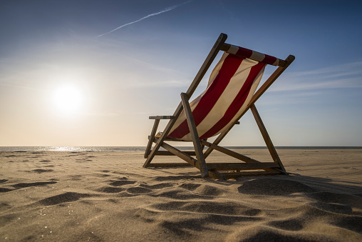 Lounge Chair on sunny day at beach. Sunset over the sea. Taken brightly lit from low angle view and rear view with copy space close to Leeuwarden, Friesland, Netherlands.