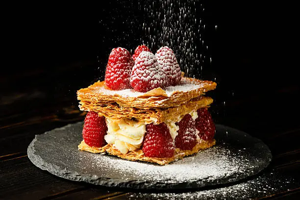 Millefeuille dessert with raspberry on black background