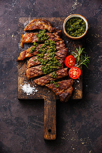 Sliced Sirloin steak with chimichurri sauce Sliced medium rare grilled beef barbecue Sirloin steak with chimichurri sauce on cutting board on dark background chimichurri stock pictures, royalty-free photos & images