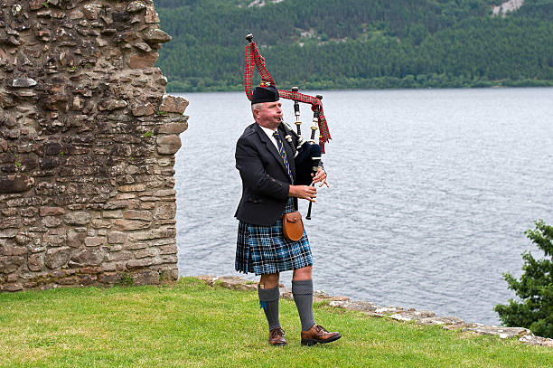 joueur de cornemuse au château d'urquhart à loch ness, écosse - loch ness scotland castle urquhart castle photos et images de collection