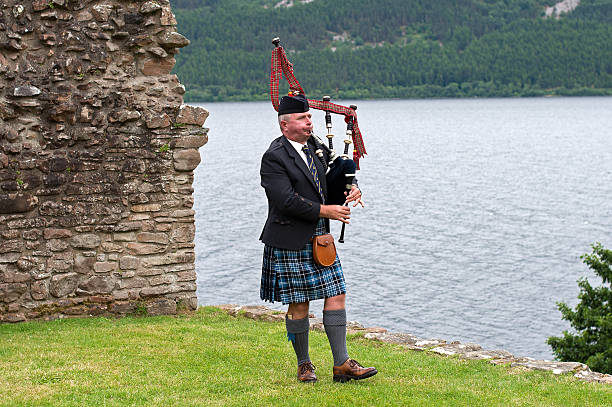 bagpiper castello di urquhart, presso il lago di loch ness, scozia - scotland castle loch ness urquhart castle foto e immagini stock