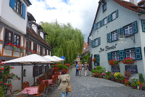 Ulm, Germany - June 23, 2015: View of a narrow street in the medieval old town. Tourists standing and walking on the street. On the right side the famous restaurant \