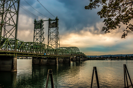 Beautiful sunset featuring dense clouds over the Interstate Bridge. A drawbridge spanning the Columbia River.  Portland, Oregon and Hayden Island is to the south as viewed from the Washington State side of the river in Vancouver, WA. Riverfront, Waterfront, No People, Horizontal landscape. USA