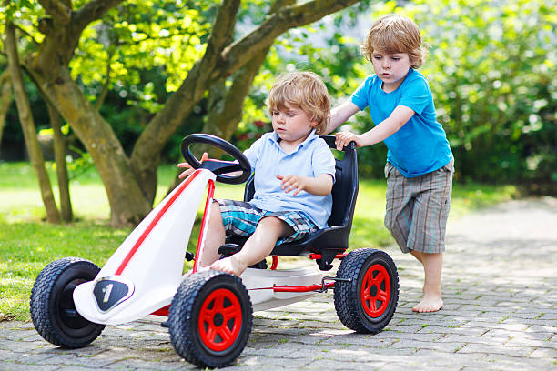 istock Two happy twin boys driving toy car 498952381