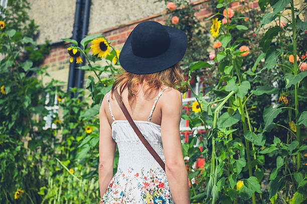 istock Woman with hat looking at sunflowers 498954234
