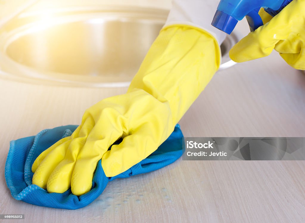 Cleaning kitchen countertop Close up of female hands with protective gloves cleaning kitchen countertop 2015 Stock Photo