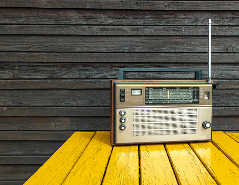 Old radio on wooden yellow table.