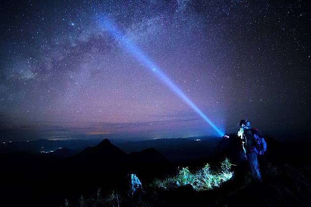 istock Young man Shining a flashlight on Mountain with night sky 498976847
