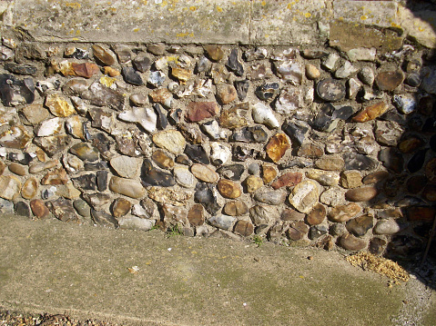 Pieces of flint cut, knapped with stones set into the stone of a church wall base.