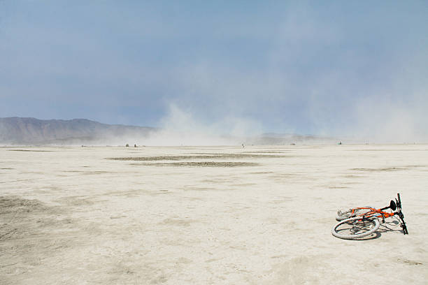 Burning Man - A Dry Wind Burning Man 2013 - A bicycle abandoned on the playa, dust storm in the distance salt flat stock pictures, royalty-free photos & images