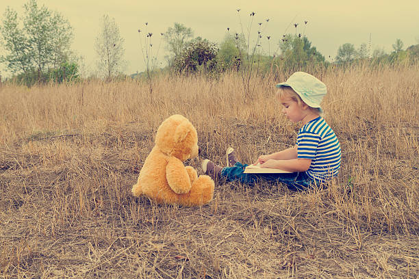 istock Cute girl reading book Teddy bear 498982202